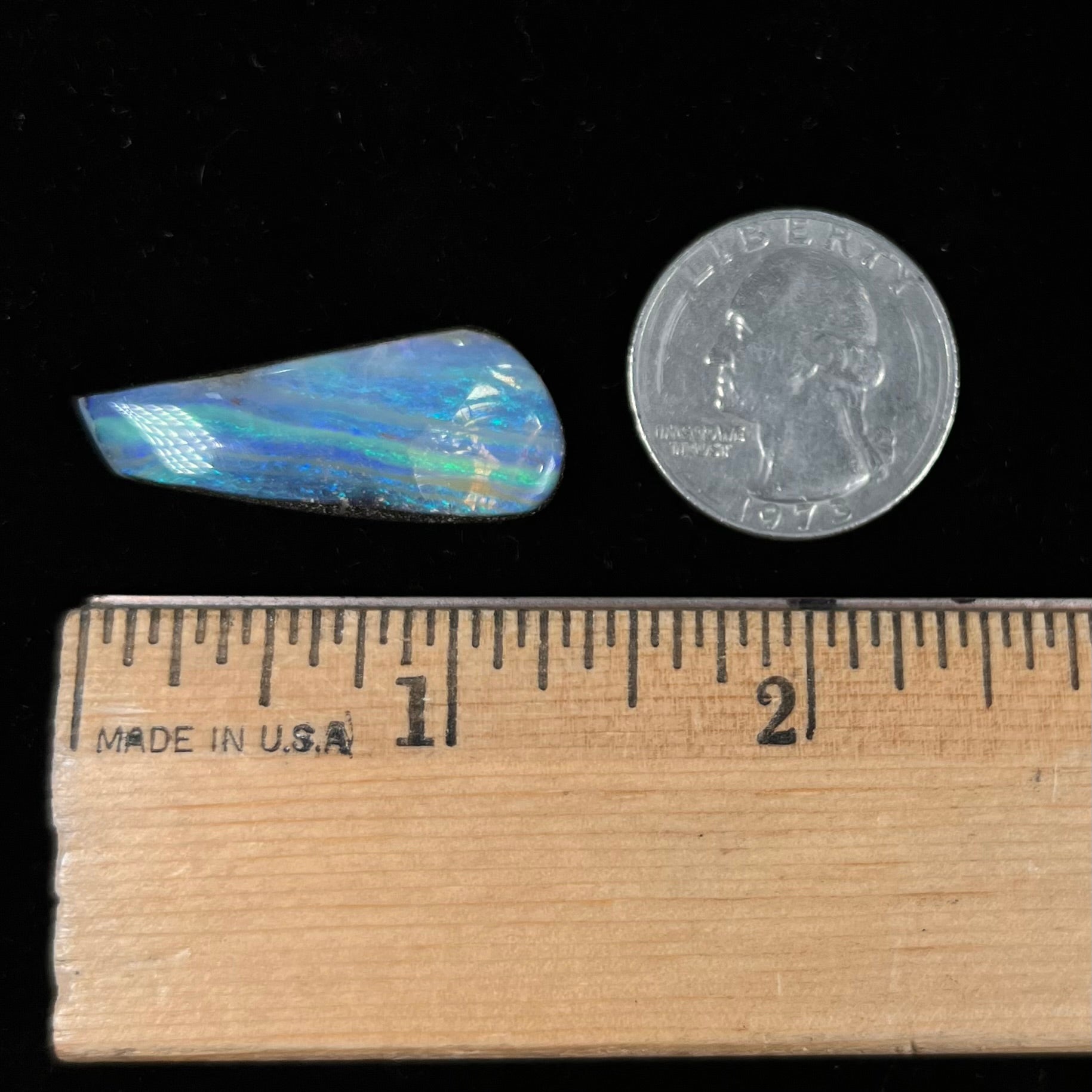 A loose, polished, freeform drop shaped boulder opal stone from Quilpie, Australia.