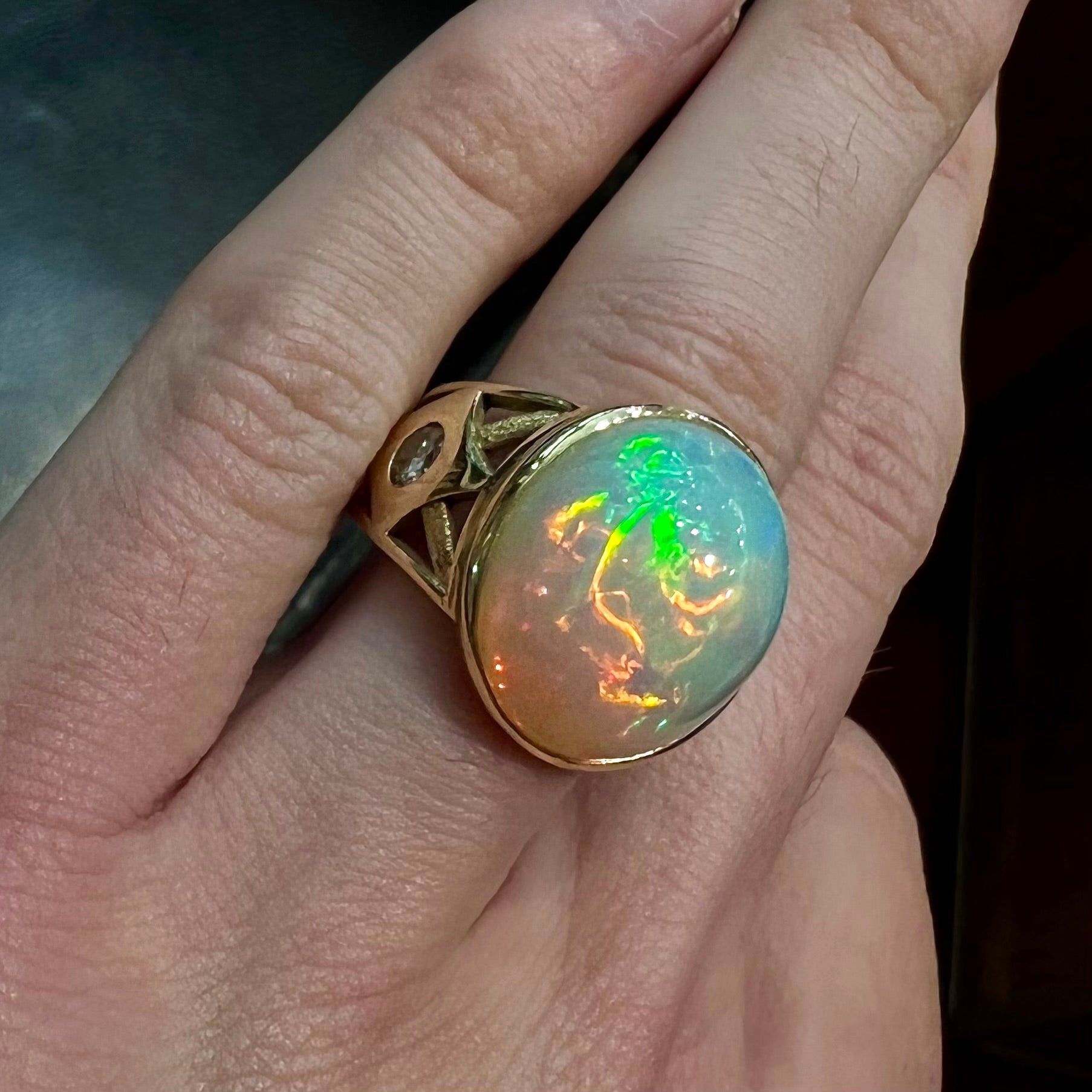 A custom yellow gold men's ring set with two diamonds and a large oval cabochon cut opal from Ethiopia, Africa.