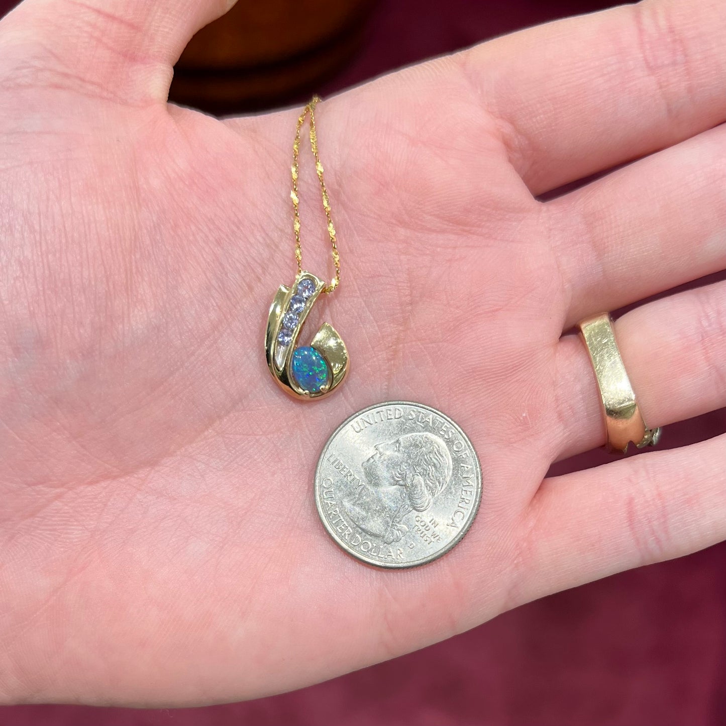 A Lightning Ridge black crystal opal necklace set with blue tanzanite in yellow gold.  Gold chain not included.