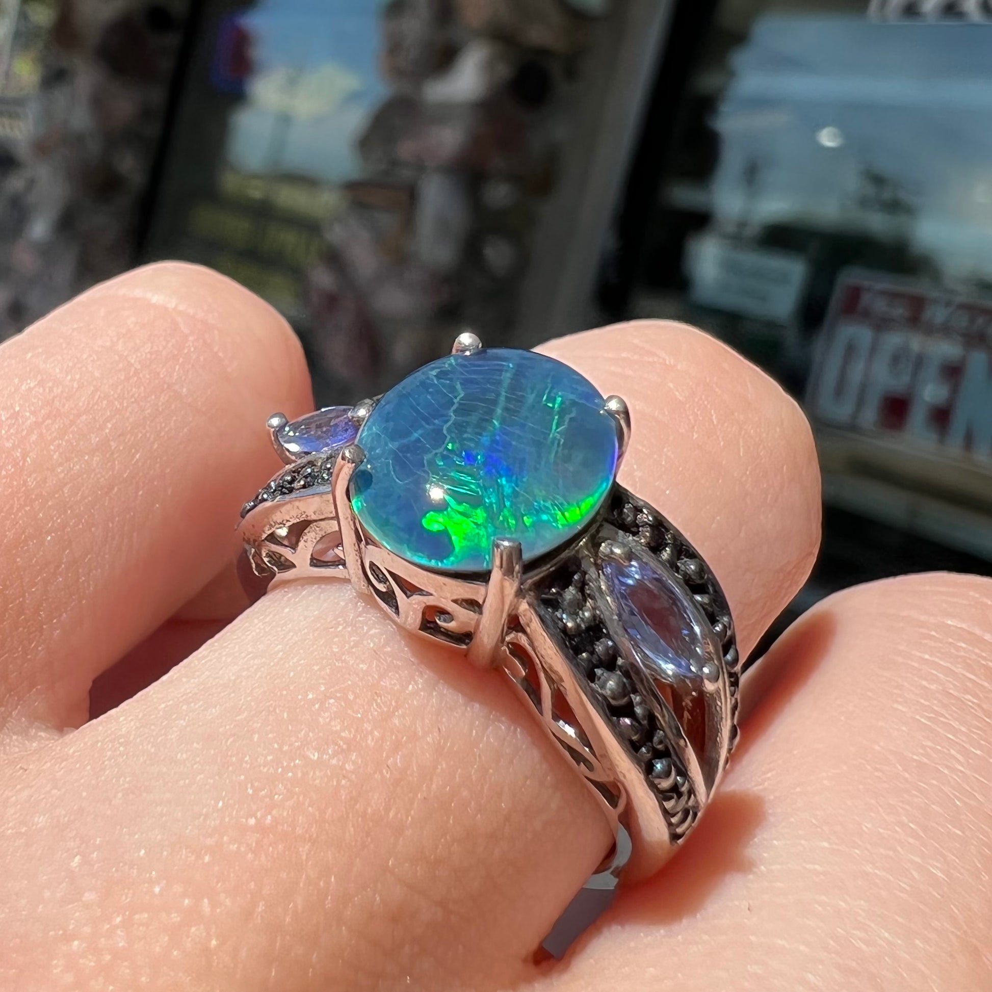 A sterling silver ring set with a black opal triplet, two marquise cut tanzanites, and round black spinel accent stones.