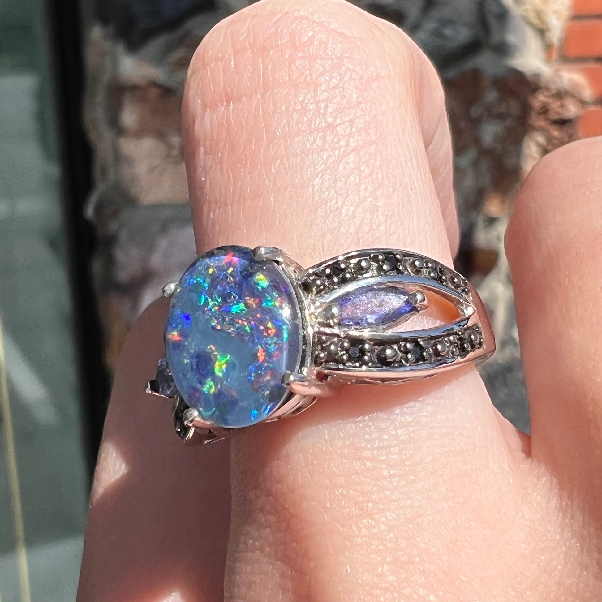 A sterling silver black opal triplet ring set with black spinel and marquise cut tanzanite accent stones.