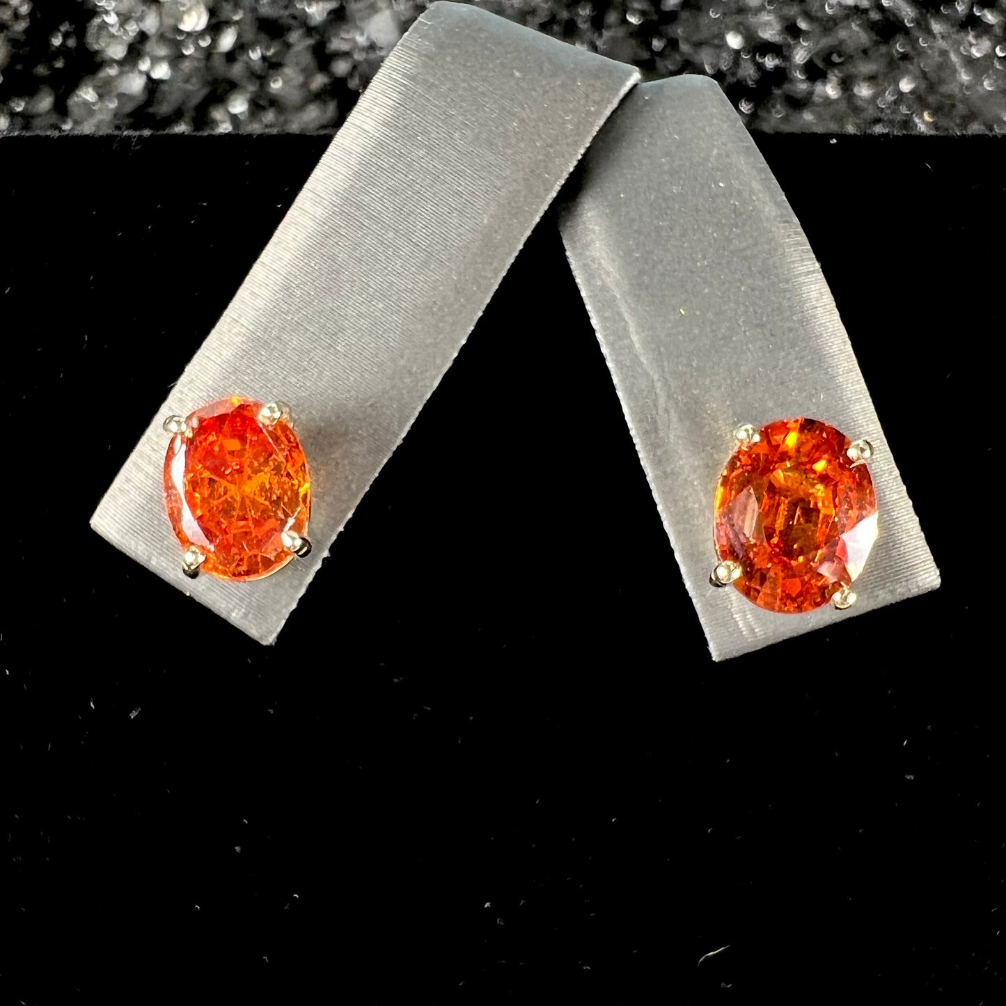 A pair of yellow gold orange hessonite garnet stud earrings.  The garnets are faceted oval cut.