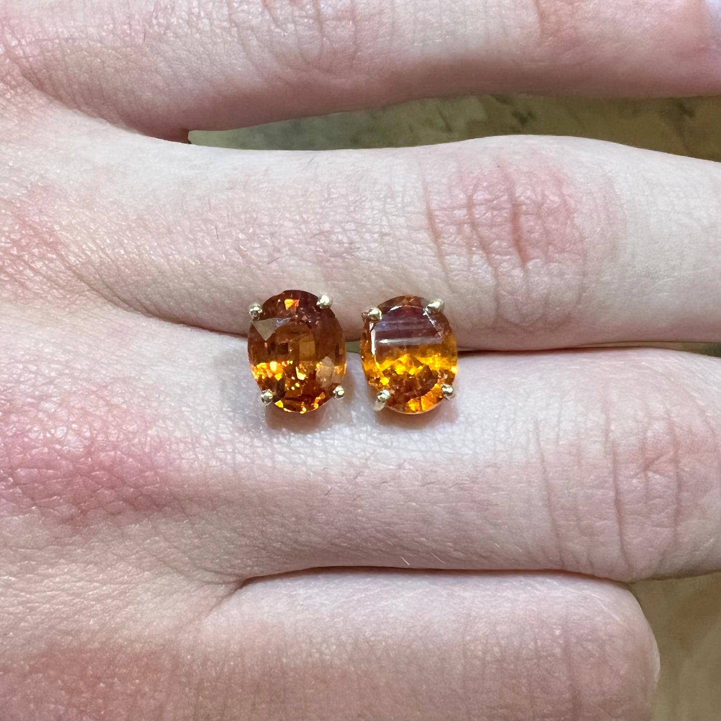 A pair of yellow gold orange hessonite garnet stud earrings.  The garnets are faceted oval cut.