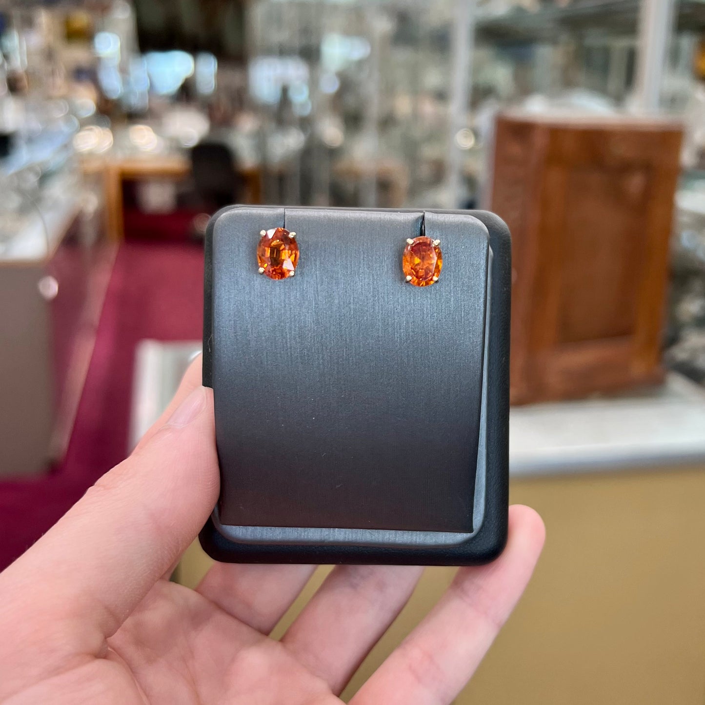 A pair of yellow gold orange hessonite garnet stud earrings.  The garnets are faceted oval cut.