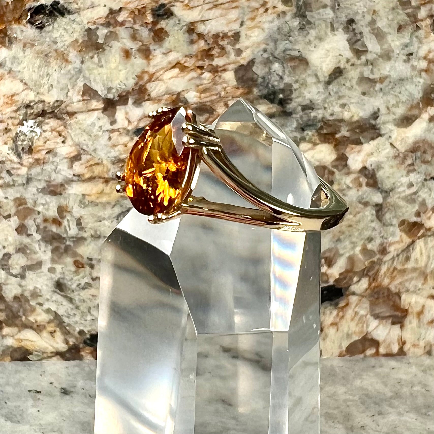 A gold split Euro shank solitaire ring set with an orange pear shape hessonite garnet stone.