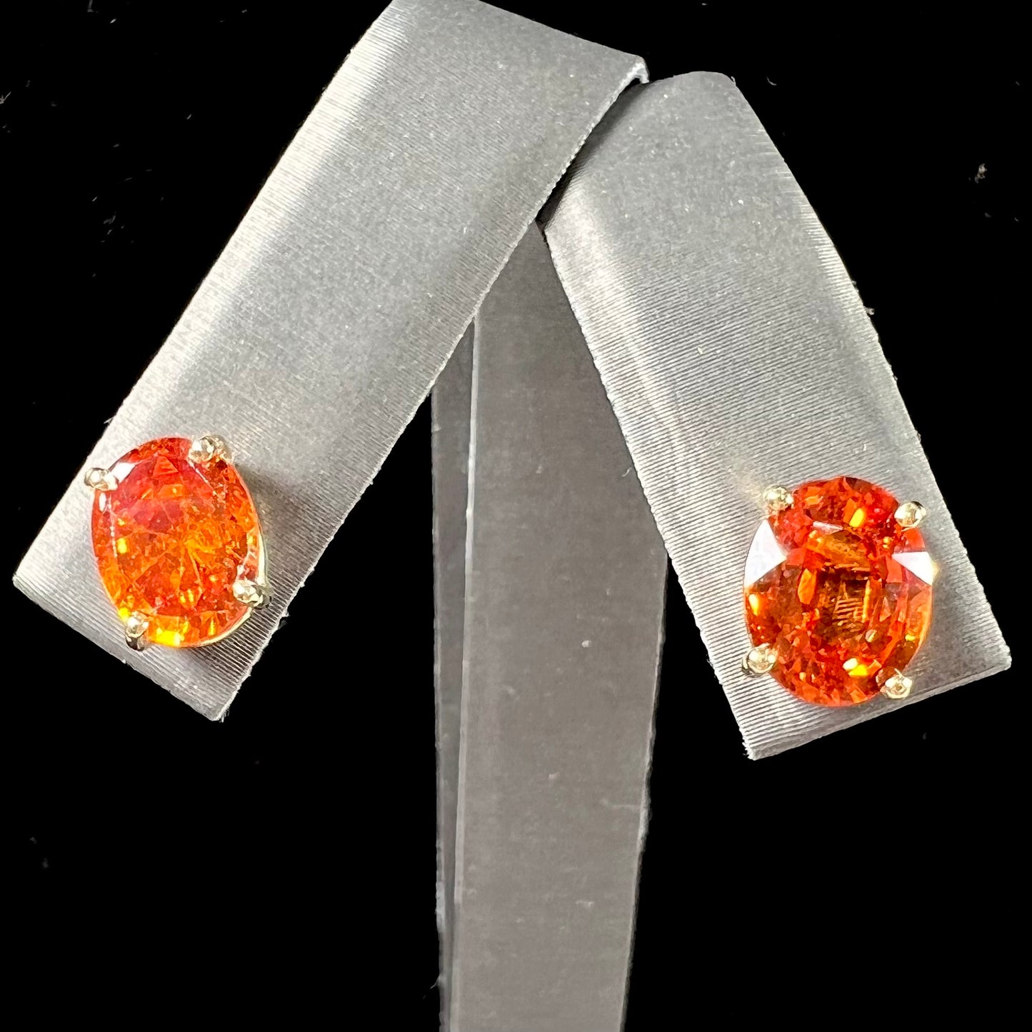 A pair of yellow gold orange hessonite garnet stud earrings.  The garnets are faceted oval cut.