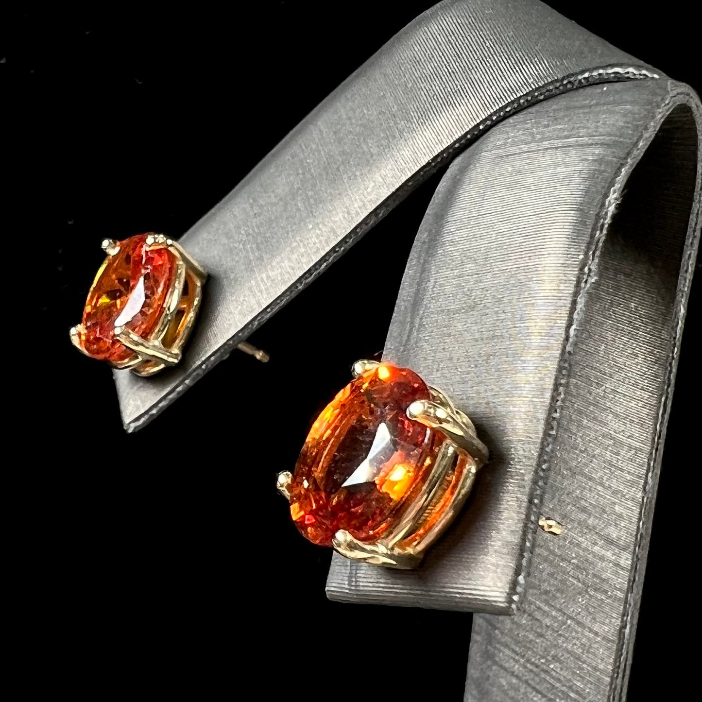 A pair of yellow gold orange hessonite garnet stud earrings.  The garnets are faceted oval cut.