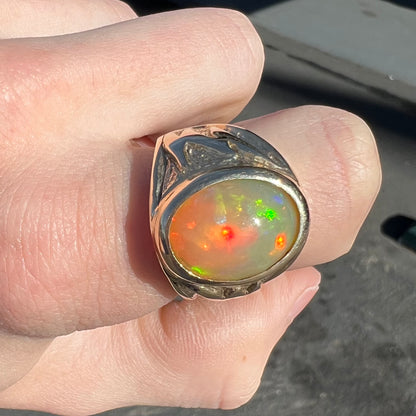 A solid yellow gold solitaire men's fire opal ring.  The stone is an orange oval cabochon cut.