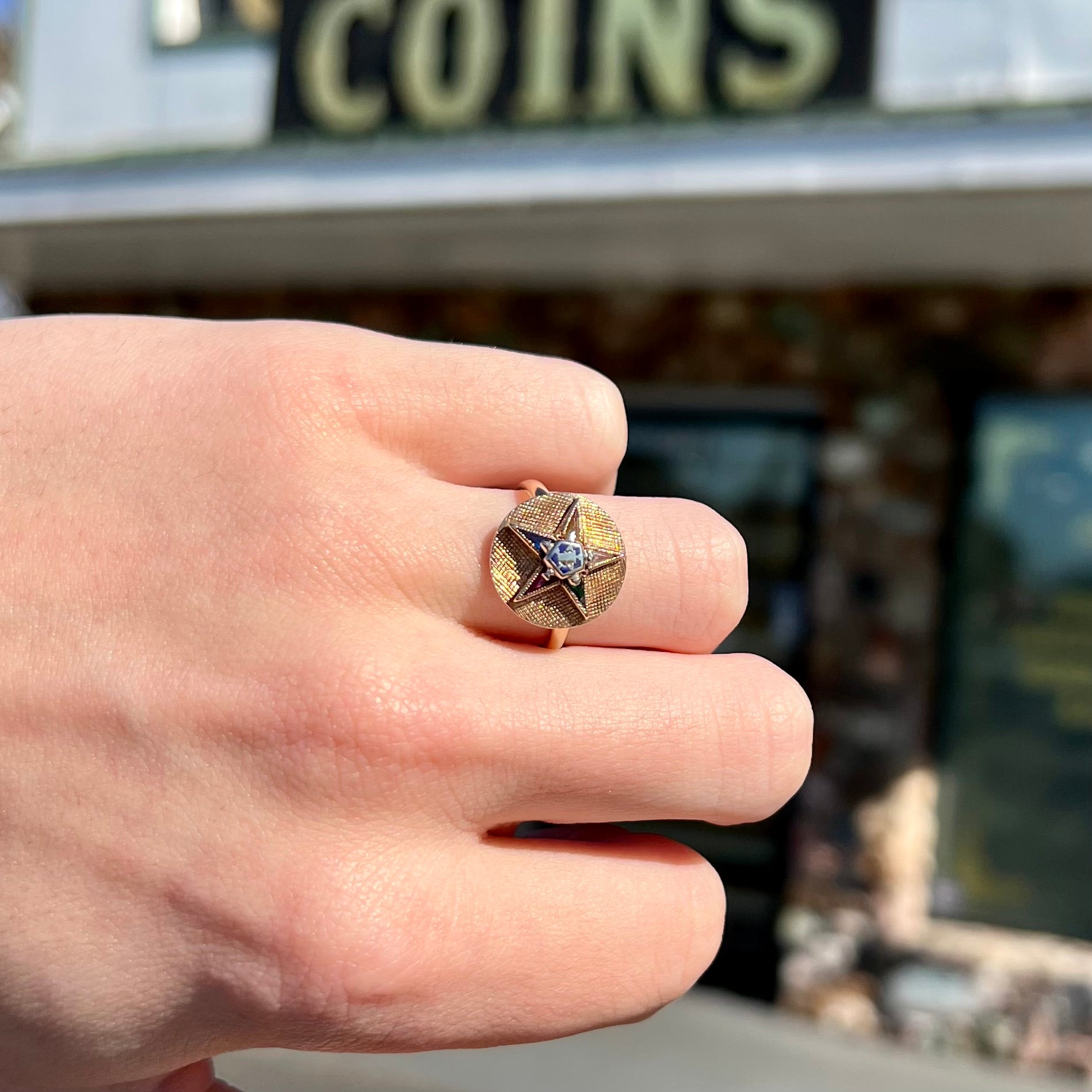 A gold ring set with multicolored synthetic sapphires forming a star with a blue enameled center, symbolizing the Order of the Eastern Star.