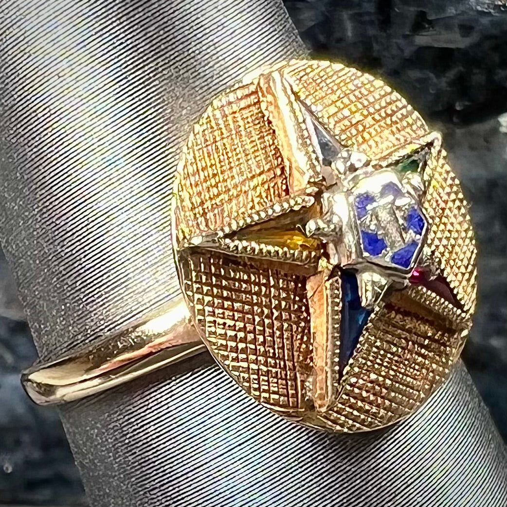 A gold ring set with multicolored synthetic sapphires forming a star with a blue enameled center, symbolizing the Order of the Eastern Star.