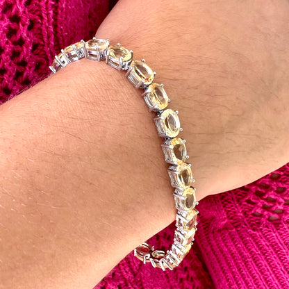 A sterling silver ladies' tennis bracelet set with faceted oval cut citrine stones.