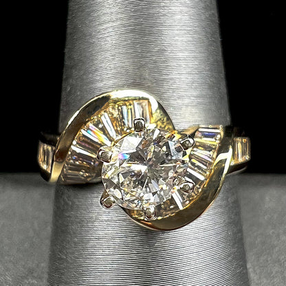 A ladies' yellow gold engagement ring set with a 0.77ct oval cut diamond and baguette cut diamond accents.