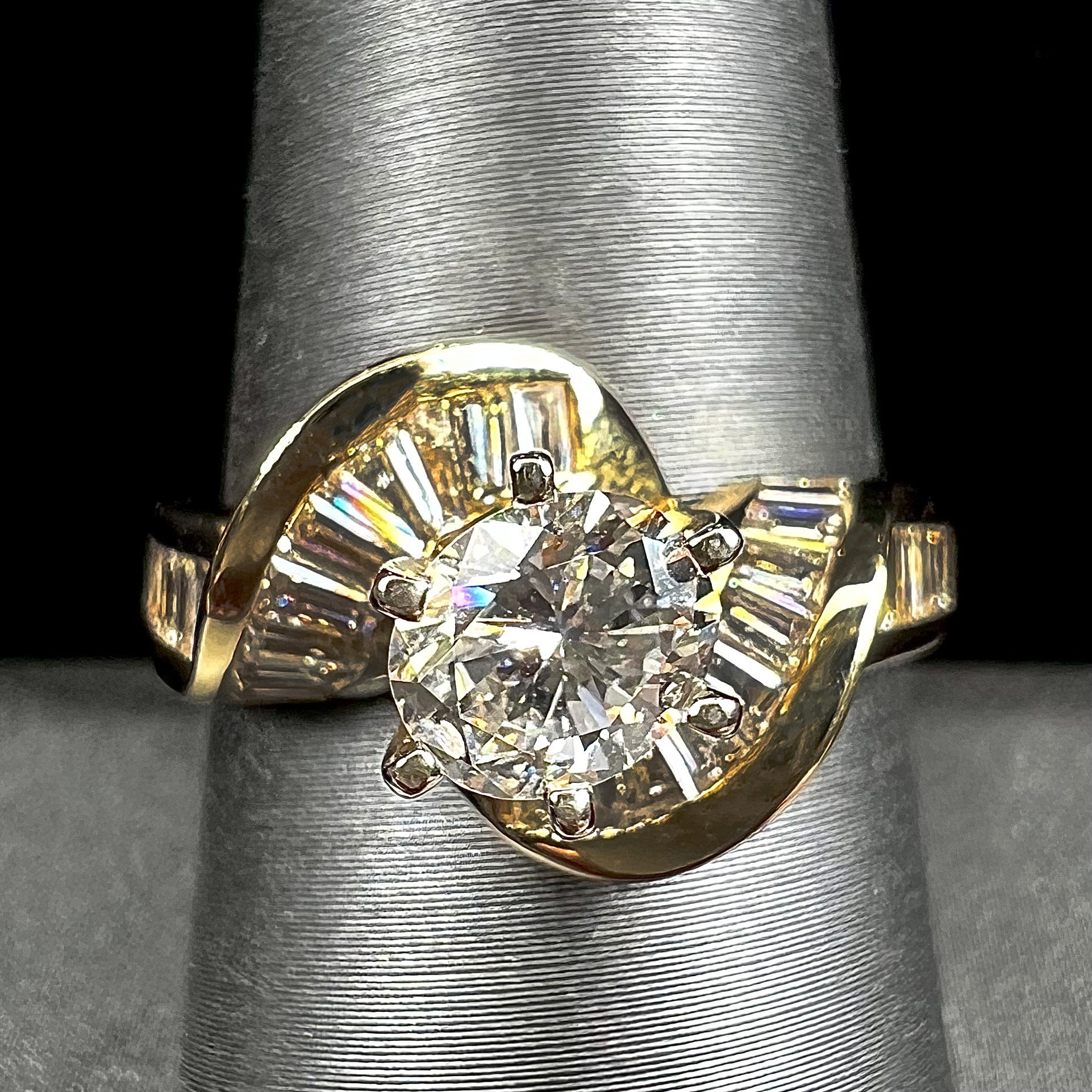 A ladies' yellow gold engagement ring set with a 0.77ct oval cut diamond and baguette cut diamond accents.