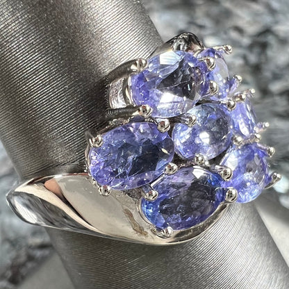 A sterling silver cluster ring prong set with seven faceted oval cut blue tanzanite stones.