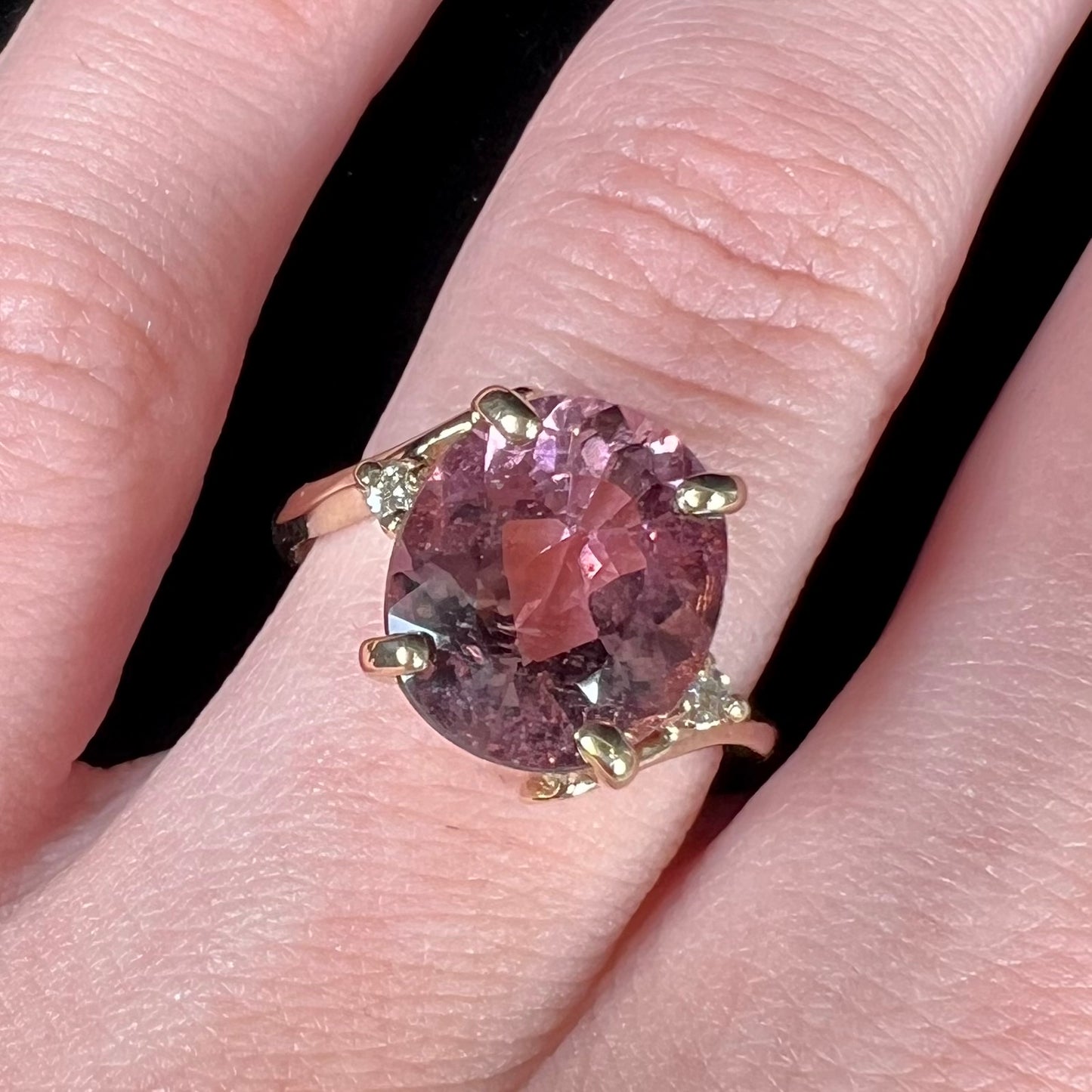 A ladies' yellow gold, faceted oval cut purple tourmaline ring set with diamond accents.