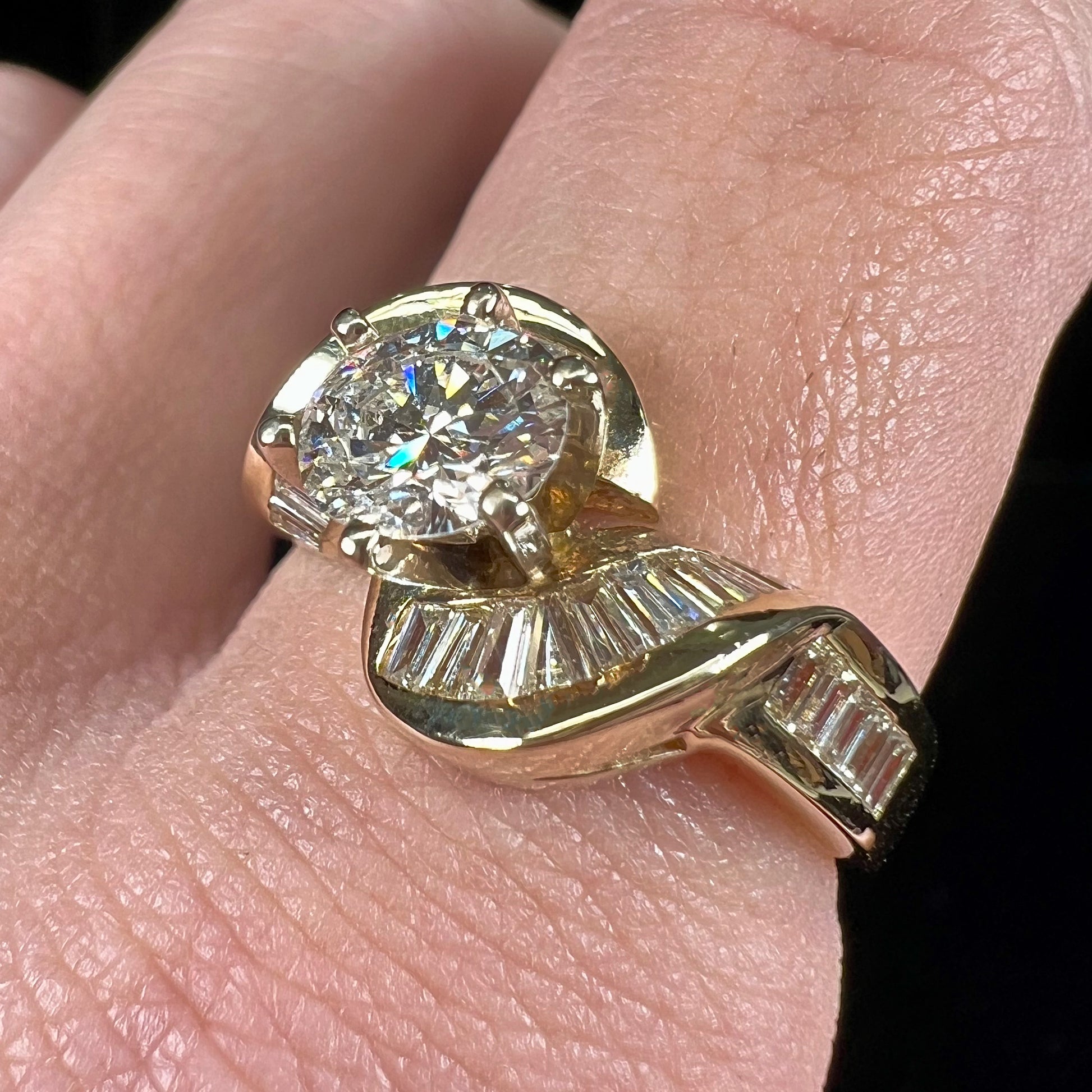 A ladies' yellow gold engagement ring set with a 0.77ct oval cut diamond and baguette cut diamond accents.