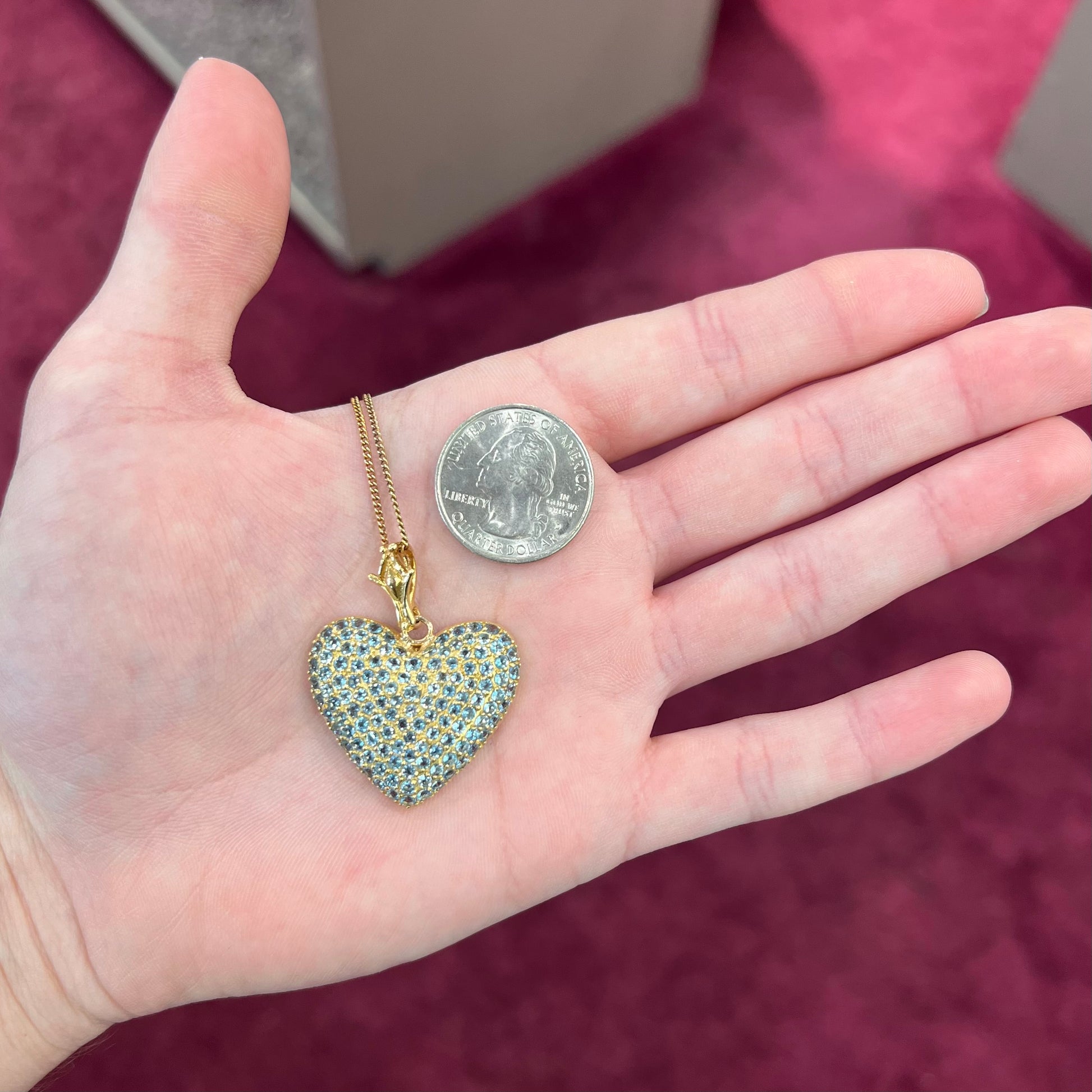 A gold heart pendant pave set with round aquamarine stones.