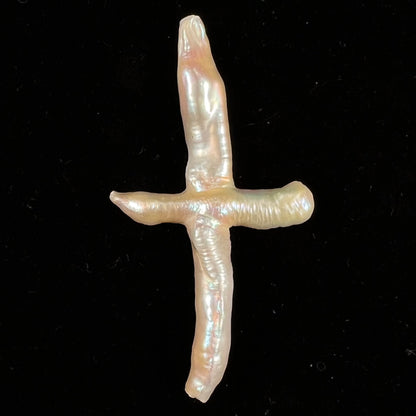A loose, cultured dark cream colored freshwater pearl cross with pink overtones.