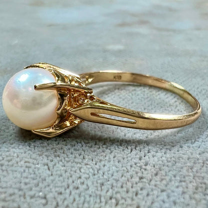 Round white pearl with pink overtones set in a vintage 18k yellow gold ring.