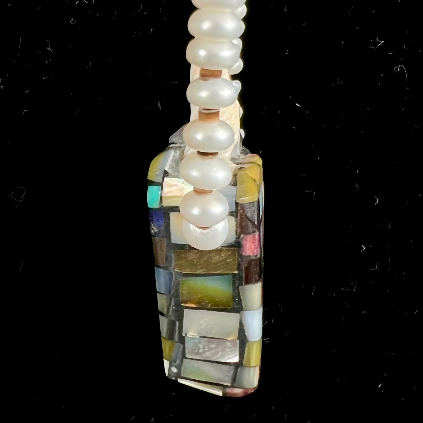 A seashell necklace that has been inlaid with spiny oyster and mother of pearl shell on a pearl bead necklace by Charlene Reano.