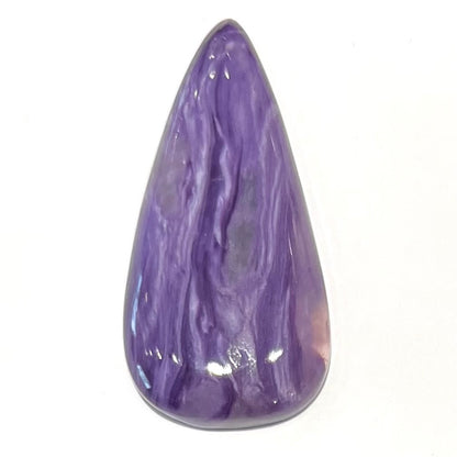 A pear shaped cabochon cut purple charoite stone.