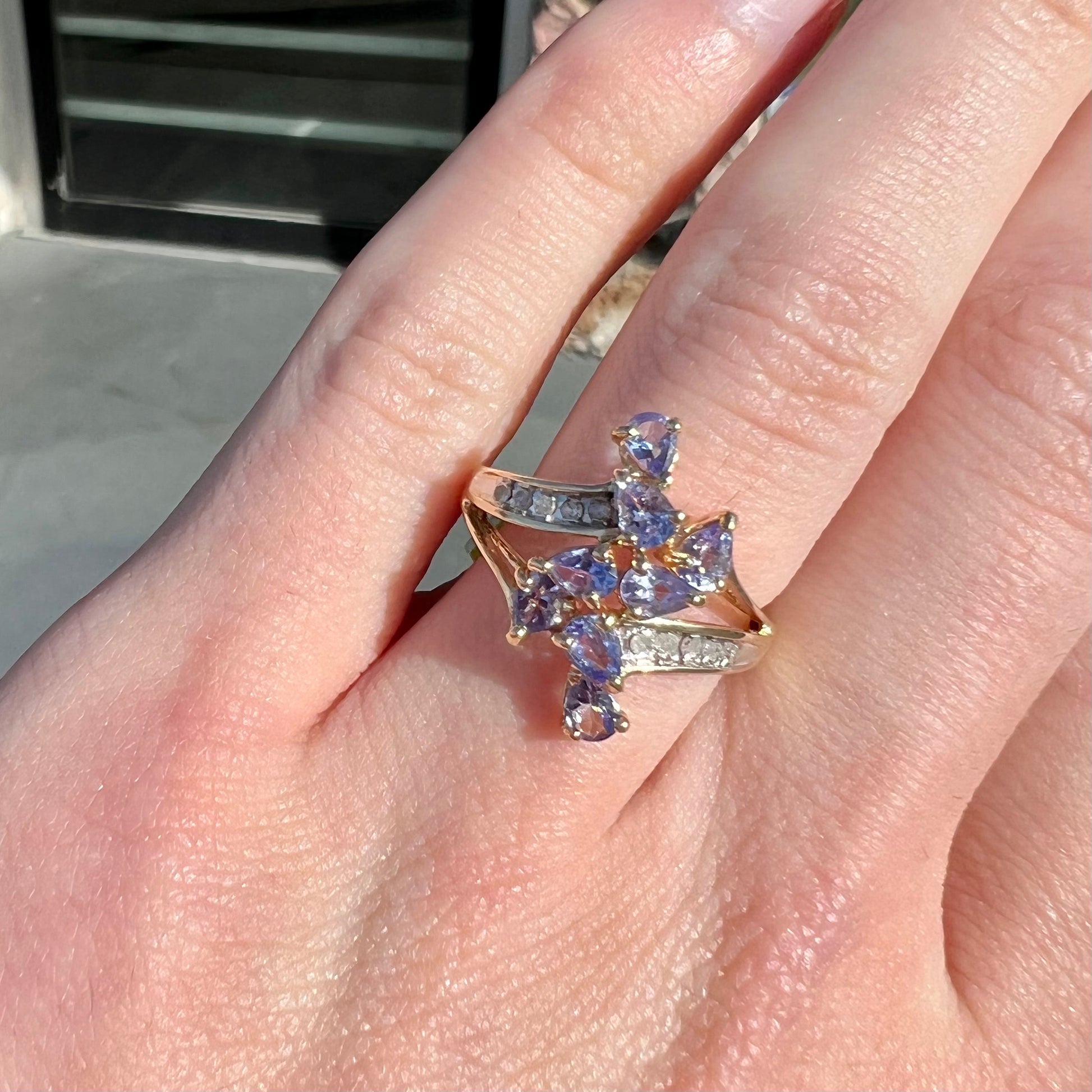 A pear shape tanzanite cluster ring channel set with diamonds in yellow gold.