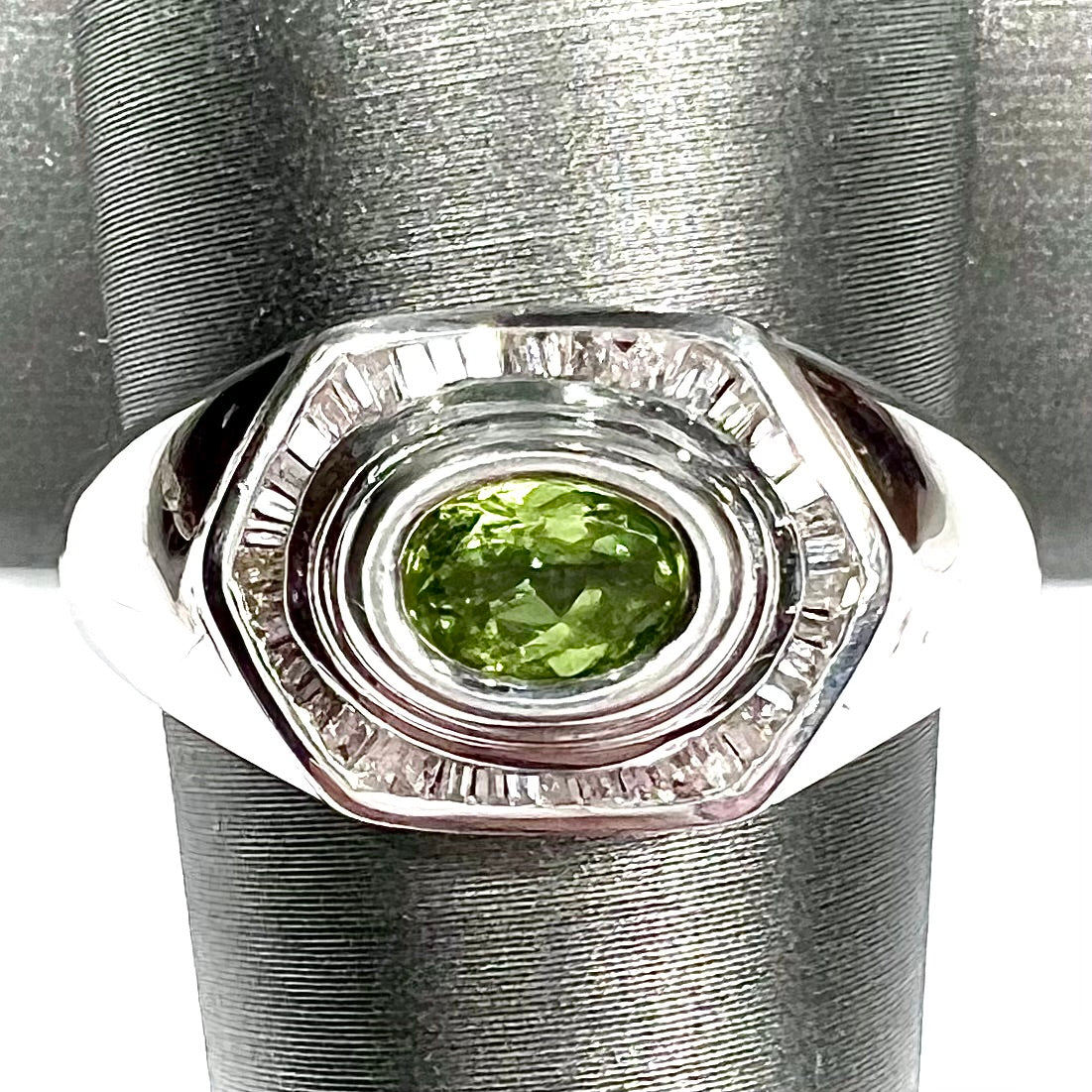 A sterling silver men's ring set with green peridot surrounded by baguette cut diamonds.