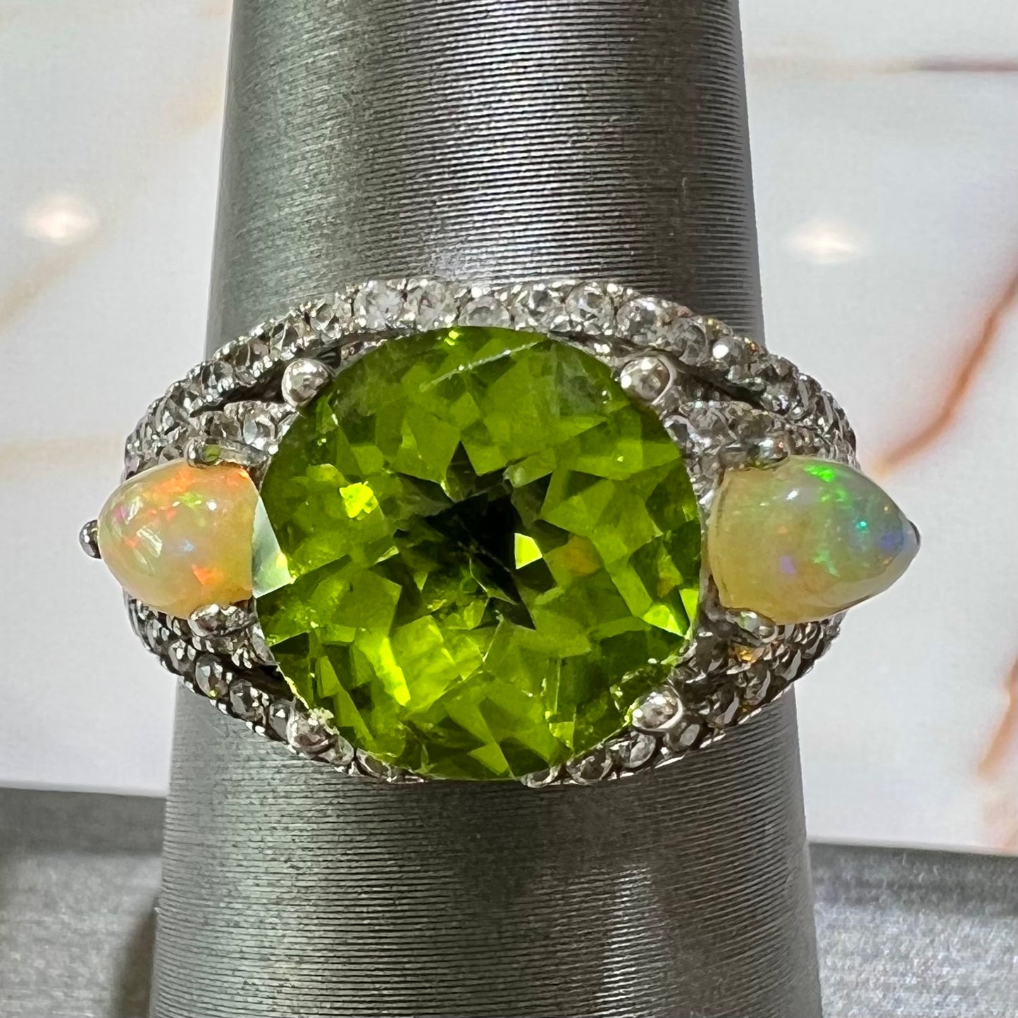 A sterling silver ring set with one large round peridot stone set between two pear shape cabochon Ethiopian opals.  Cubic zirconia stones line the ring.