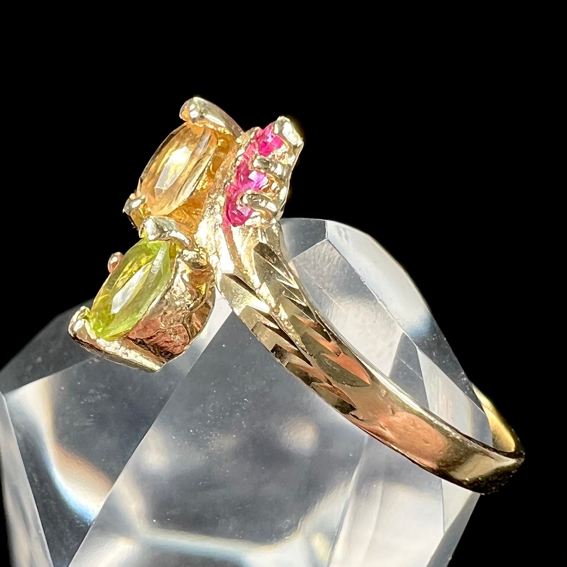 A gold twisted shank ring set with a marquise cut citrine, marquise cut peridot, and round cut ruby accents.