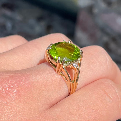A ladies' round brilliant cut peridot statement ring set with two round diamond accents in yellow gold.