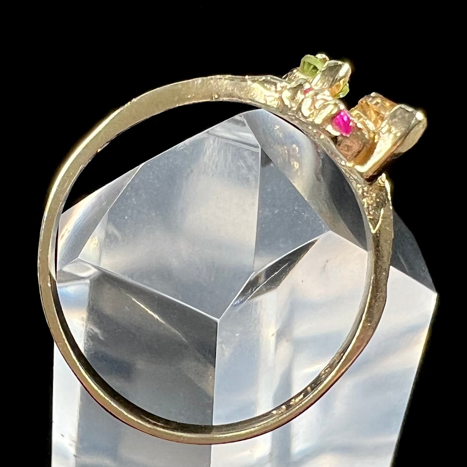 A gold twisted shank ring set with a marquise cut citrine, marquise cut peridot, and round cut ruby accents.