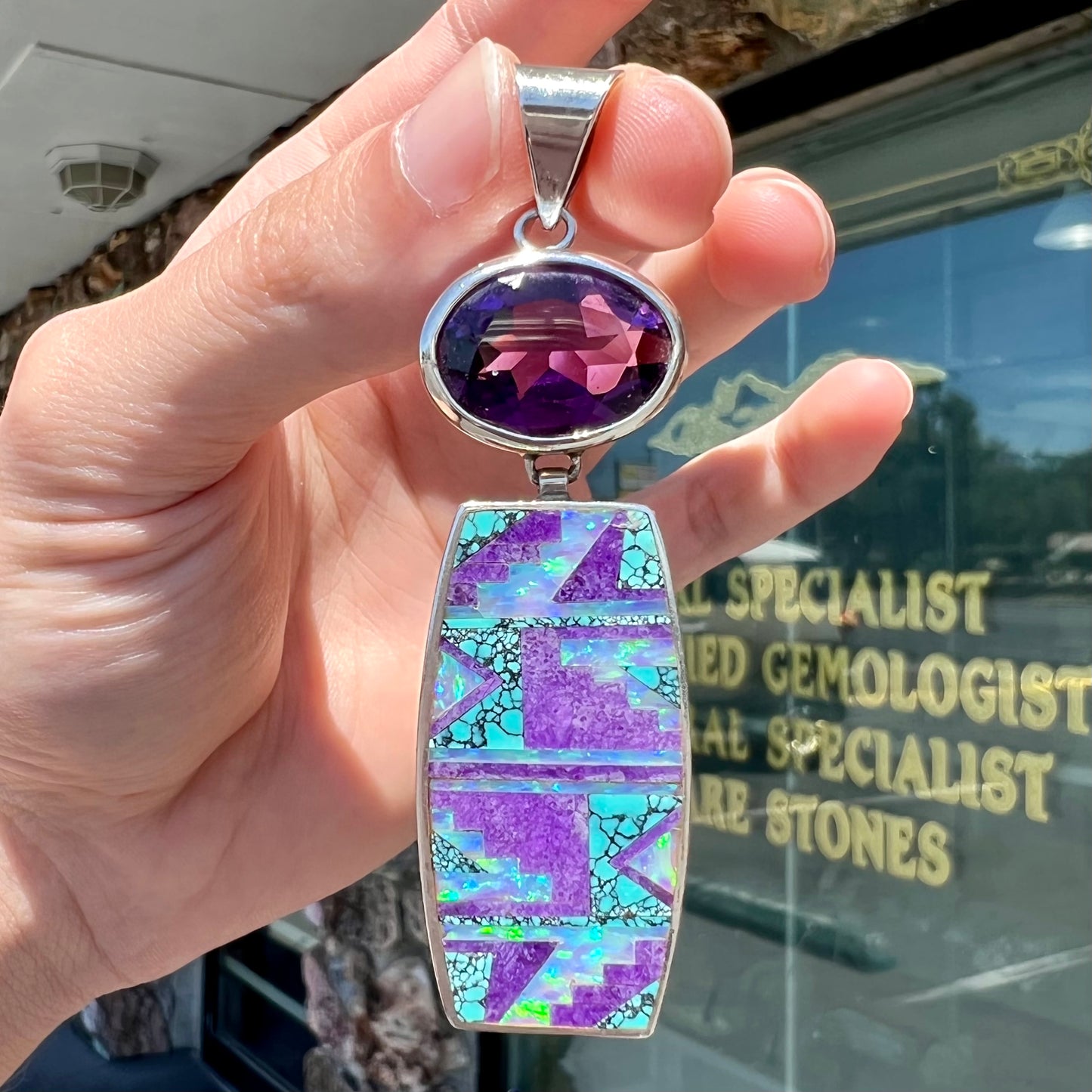 A sterling silver stone inlay necklace set with amethyst, sugilite, spiderweb turquoise, and lab created opal by Navajo artist, Peterson Chee.