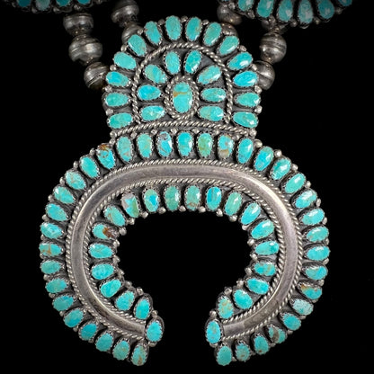 A Native American silver squash blossom turquoise petit point set with turquoise by Larry Moses Begay.