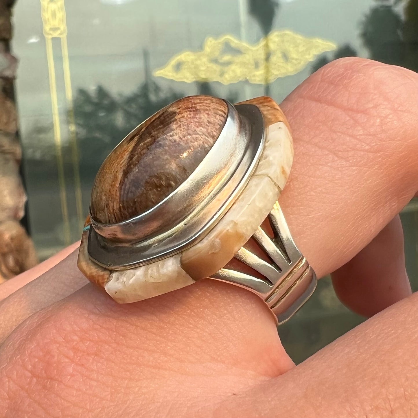 A silver ring handmade from a bezel set petrified wood stone, surrounded by quartz, carnelian, and bone inlay.