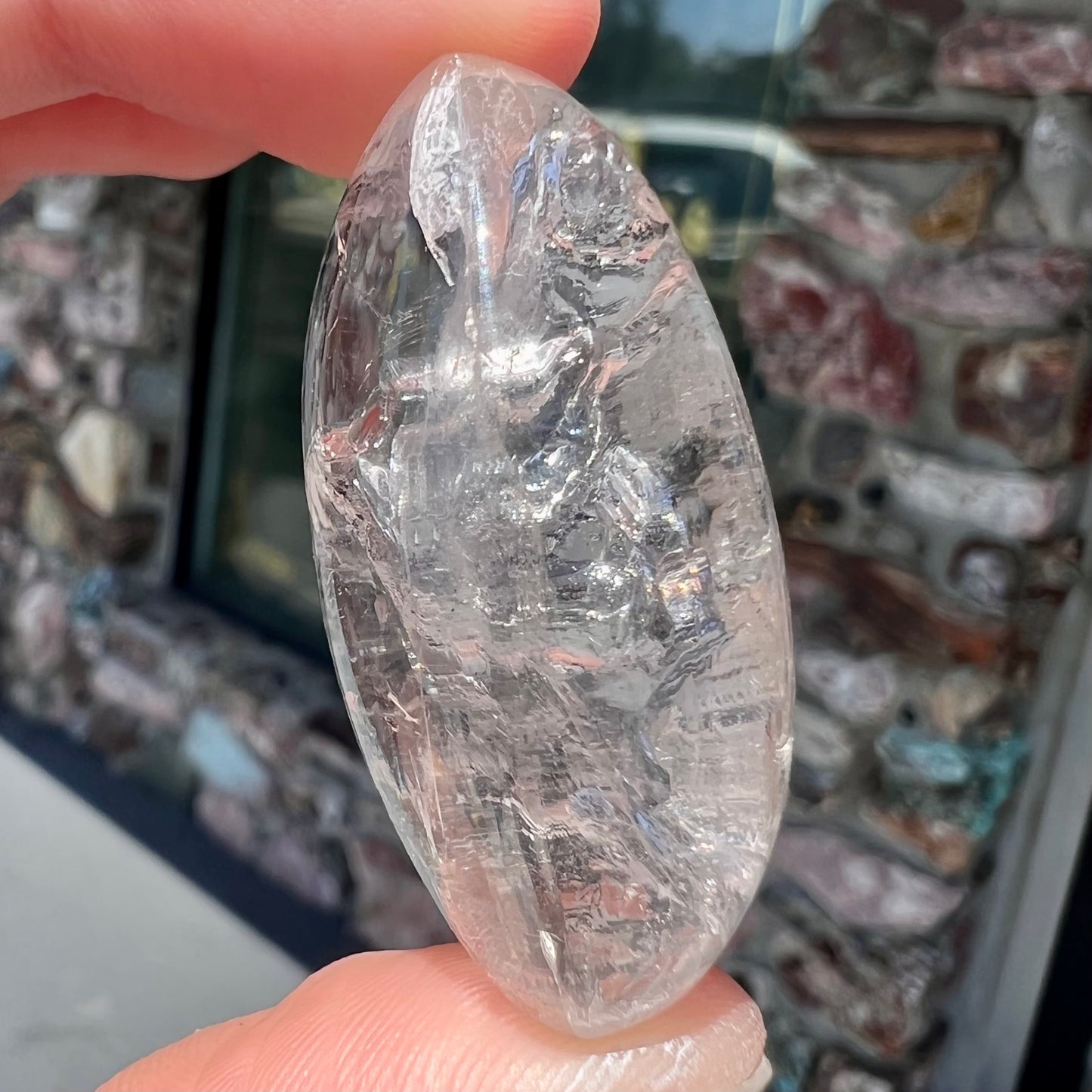 A polished clear quartz with two liquid enhydro inclusions around a solid phantom crystal inclusion.