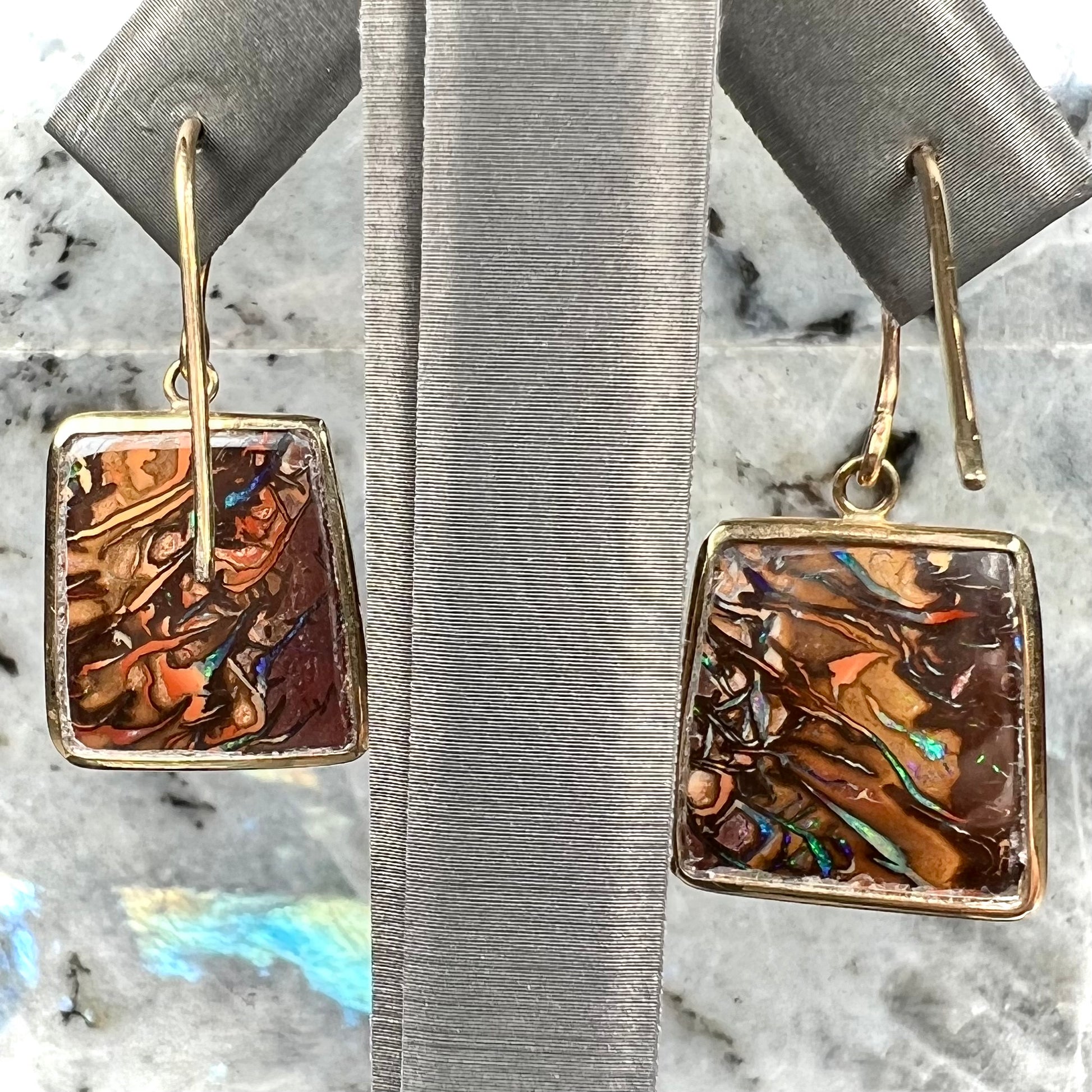 A pair of yellow gold French wire dangle earrings set with Koroit boulder opal.
