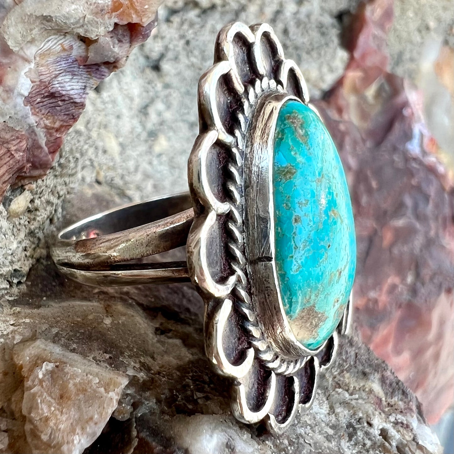 A sterling silver Navajo style ring.  The ring is set with a turquoise stone from Pilot Mountain.  There is a feather decoration next to the stone.