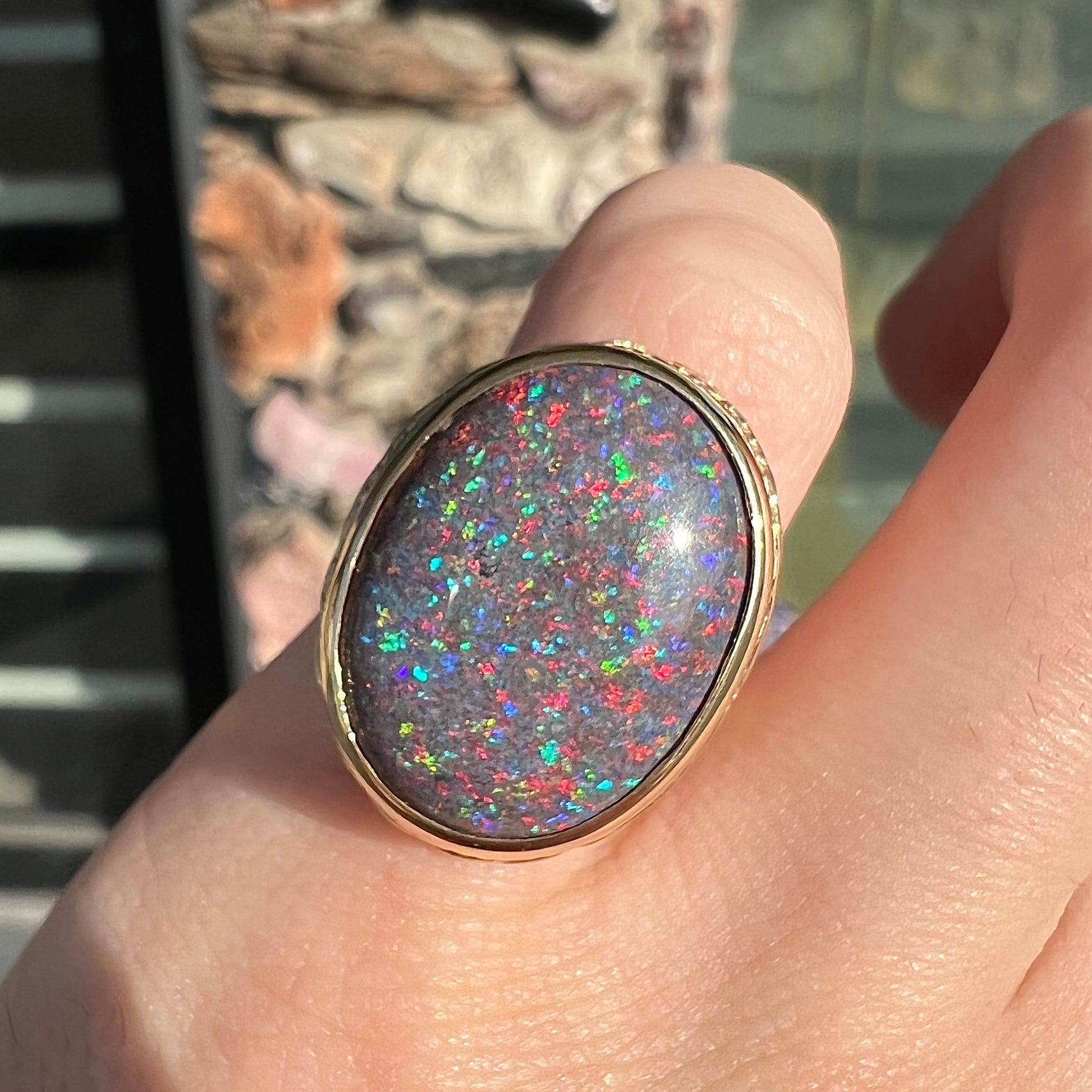 A bright black Andamooka opal that displays a pinfire pattern set in a vintage-style yellow gold bezel ring.