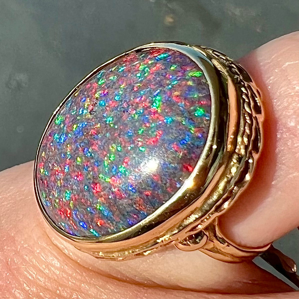 A bright black Andamooka opal that displays a pinfire pattern set in a vintage-style yellow gold bezel ring.