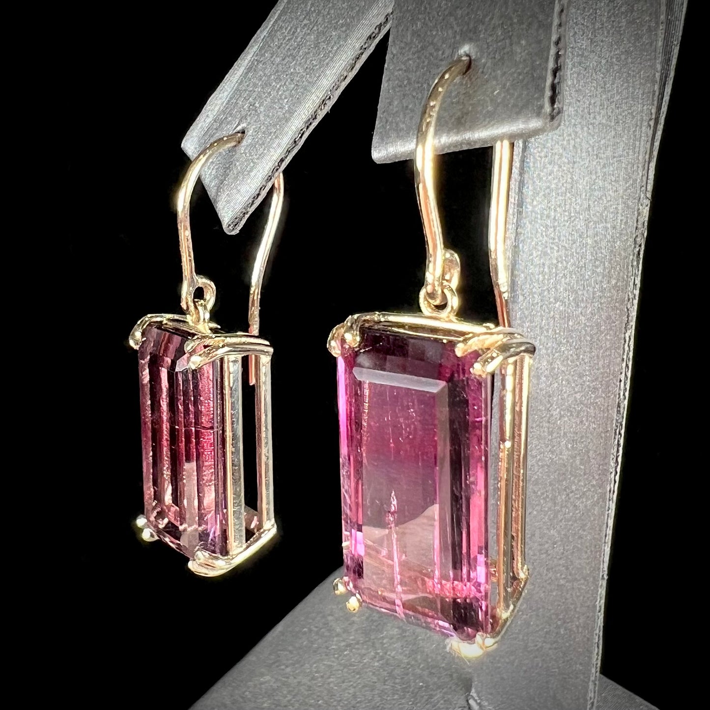 A pair of pink and magenta bicolor tourmaline dangle earrings handmade in 14kt yellow gold with basket settings and shepherd's hooks.