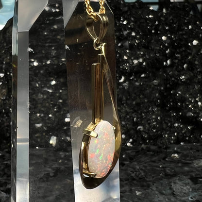 A handmade gold drop pendant set with an oval cabochon cut white crystal opal.