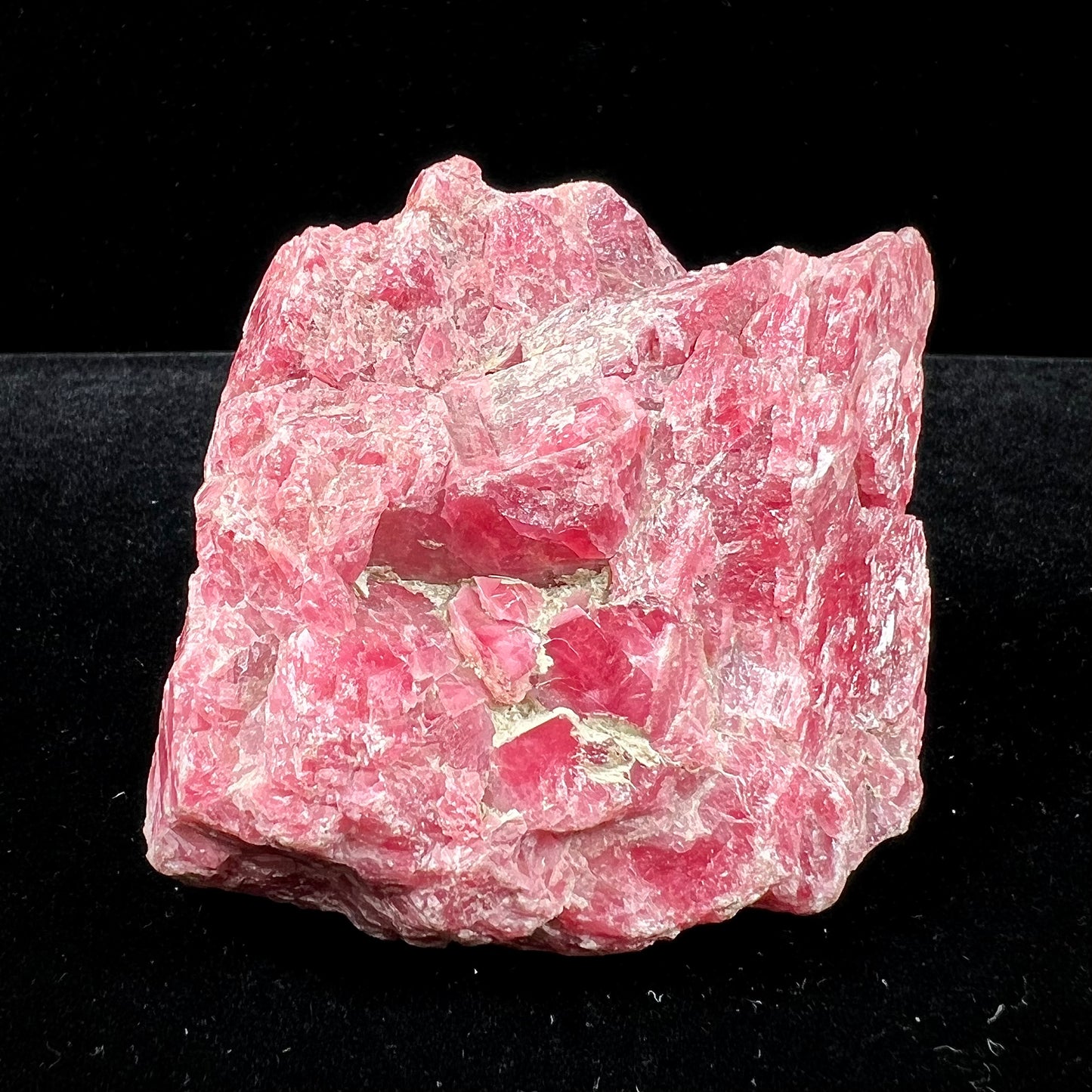 A rough pink rhodonite crystal specimen the size of a small fist.