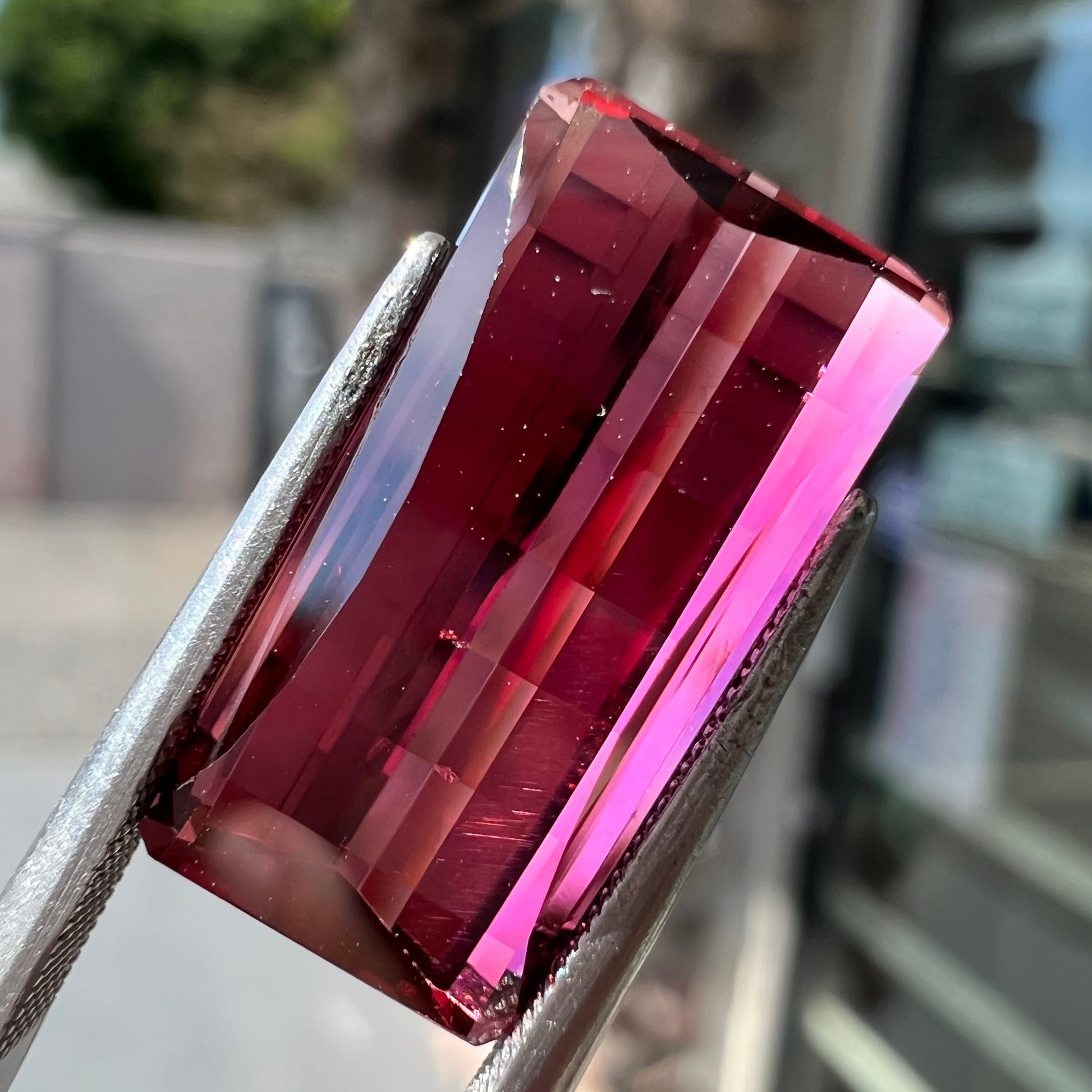 A loose, fantasy cut reddish colored tourmaline.  The cut reflects light in a way that resembles digital pixels on a screen.