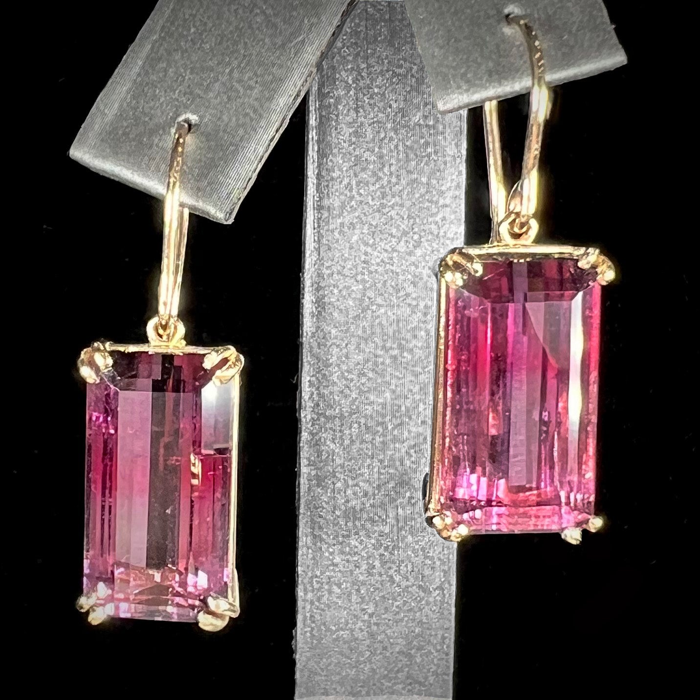 A pair of pink and magenta bicolor tourmaline dangle earrings handmade in 14kt yellow gold with basket settings and shepherd's hooks.