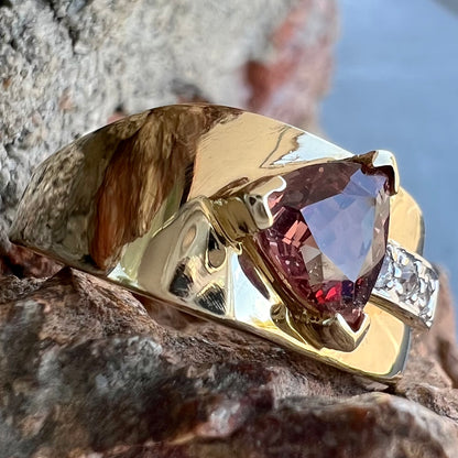 A men's gold pink tourmaline ring.  Set next to the trillion cut tourmaline is a row of three round white sapphires.