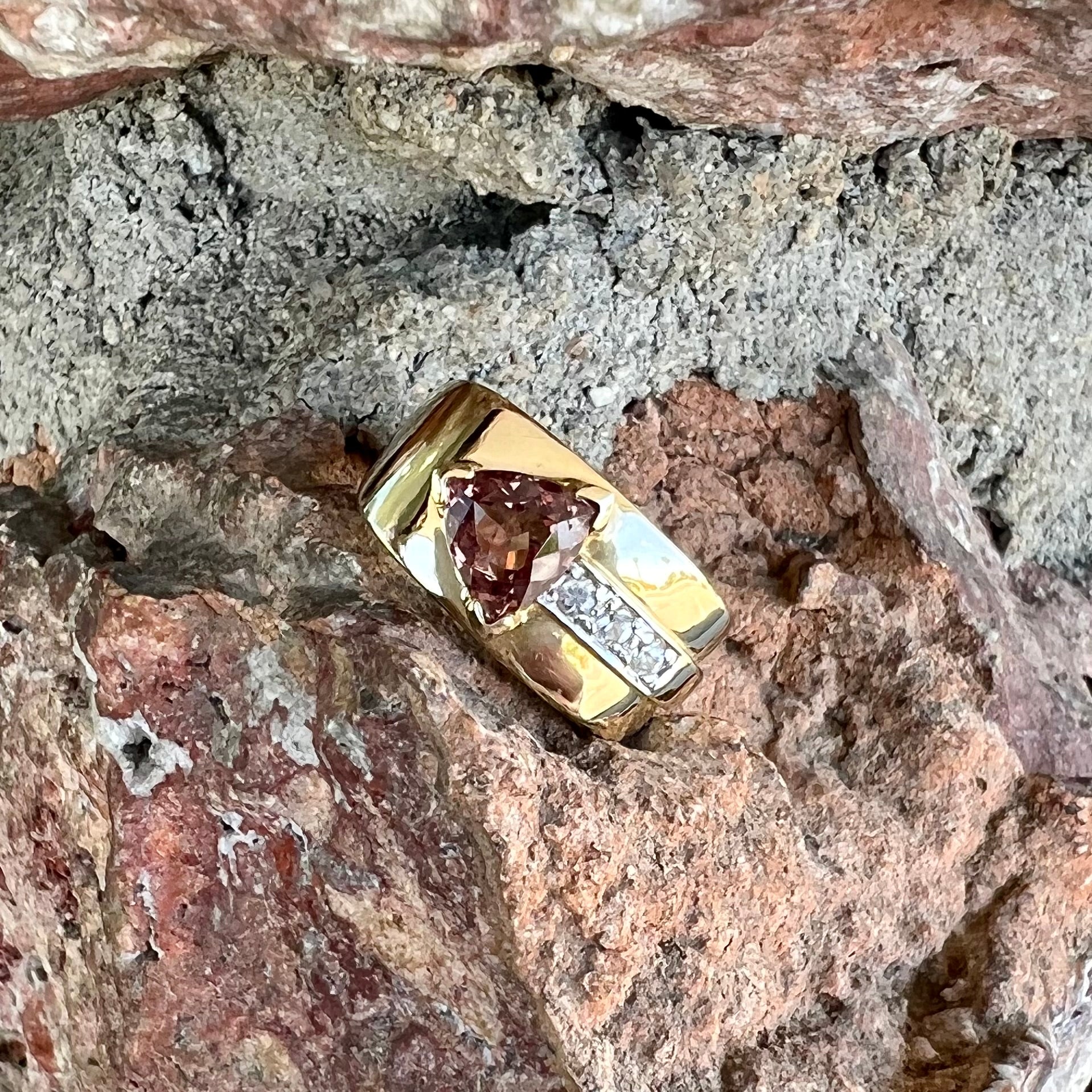A men's gold pink tourmaline ring.  Set next to the trillion cut tourmaline is a row of three round white sapphires.