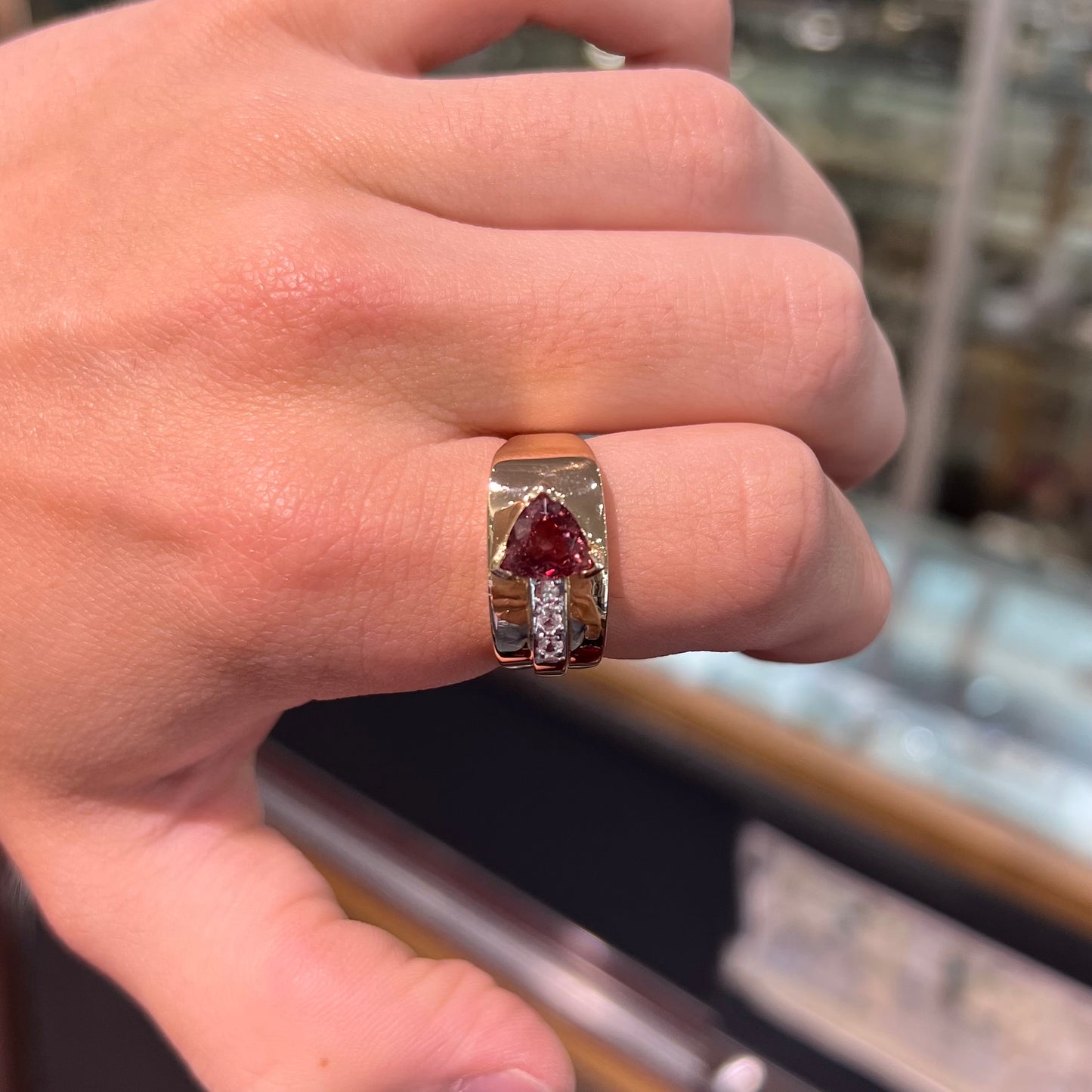 A men's gold pink tourmaline ring.  Set next to the trillion cut tourmaline is a row of three round white sapphires.