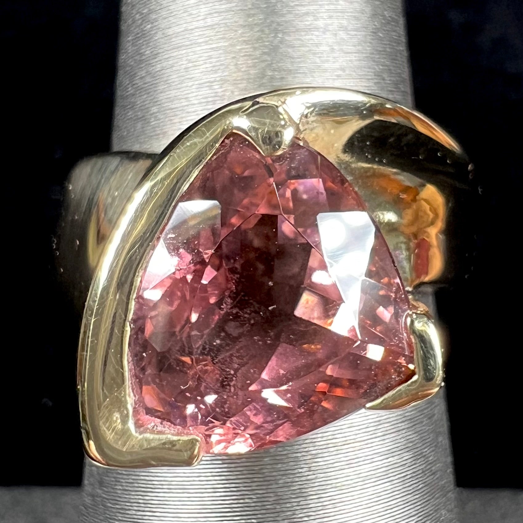 A unisex, yellow gold, trillion cut pink tourmaline solitaire ring.