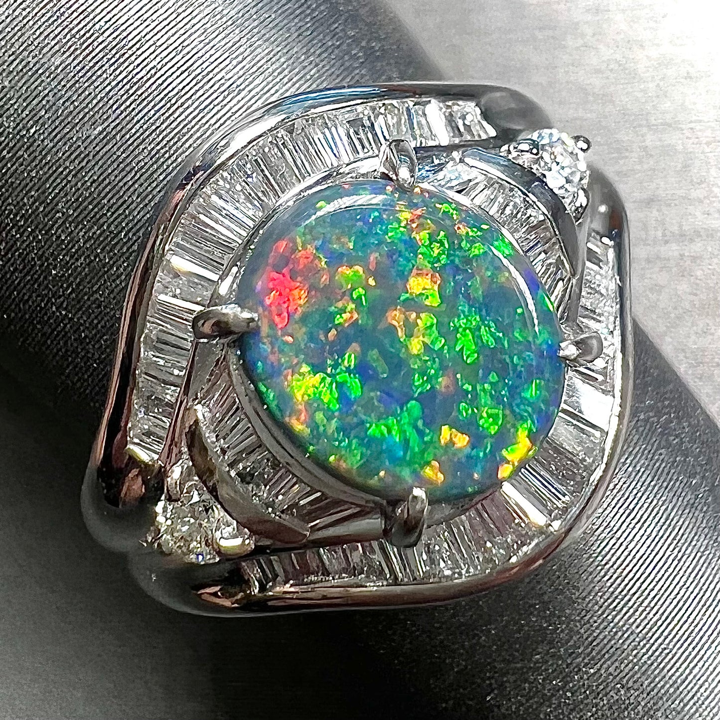 A platinum Lightning Ridge black opal ring set with baguette cut diamonds.  The opal is an oval cabochon cut.
