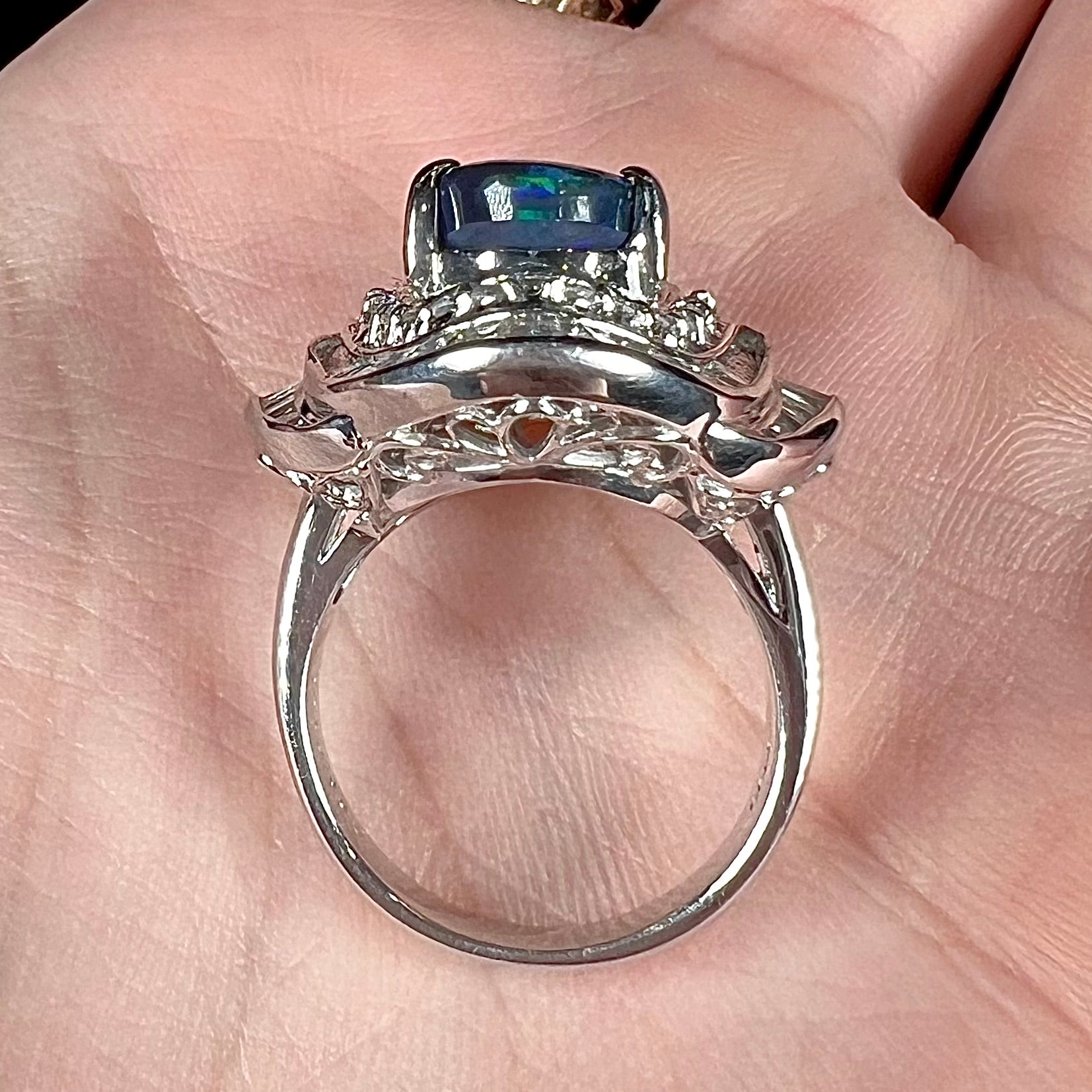 A ladies' platinum diamond halo ring set with a natural black opal stone from Lightning Ridge, Australia.